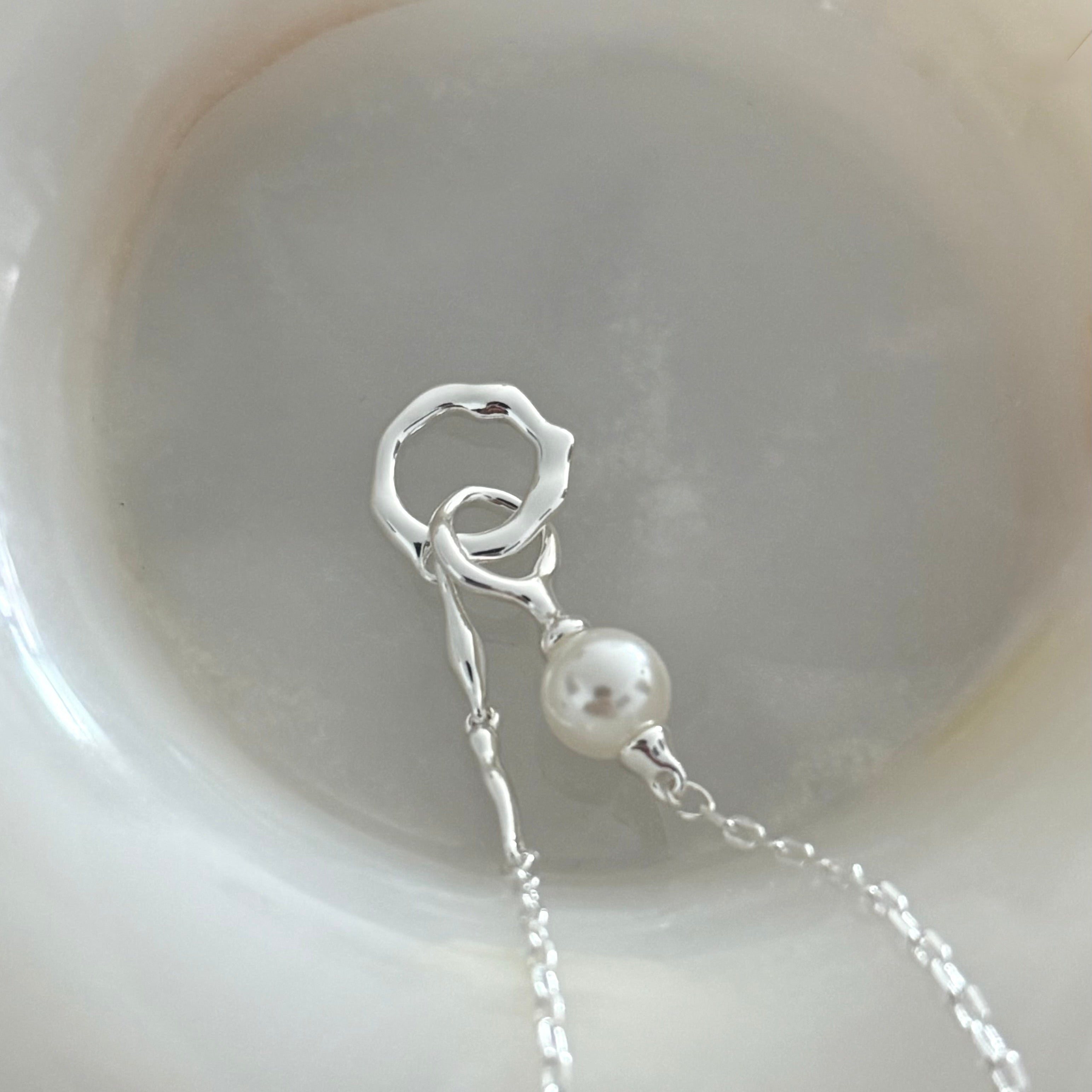 Close-up of Sonnet's textured double ring pendant in white gold, highlighting irregular texture against smooth pearl