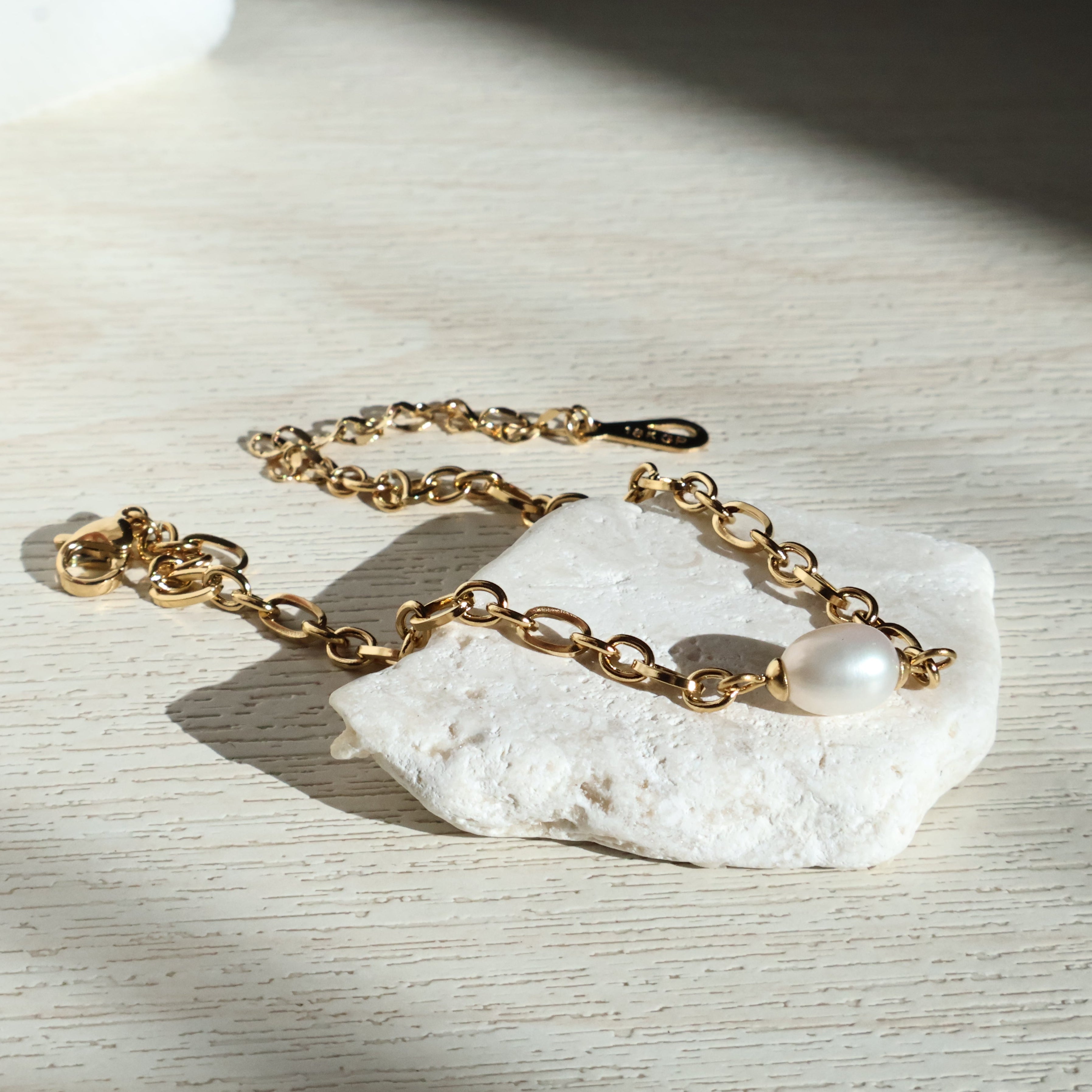 Close-up of Paige bracelet's freshwater pearl, showcasing its soft luster against the gold chain.