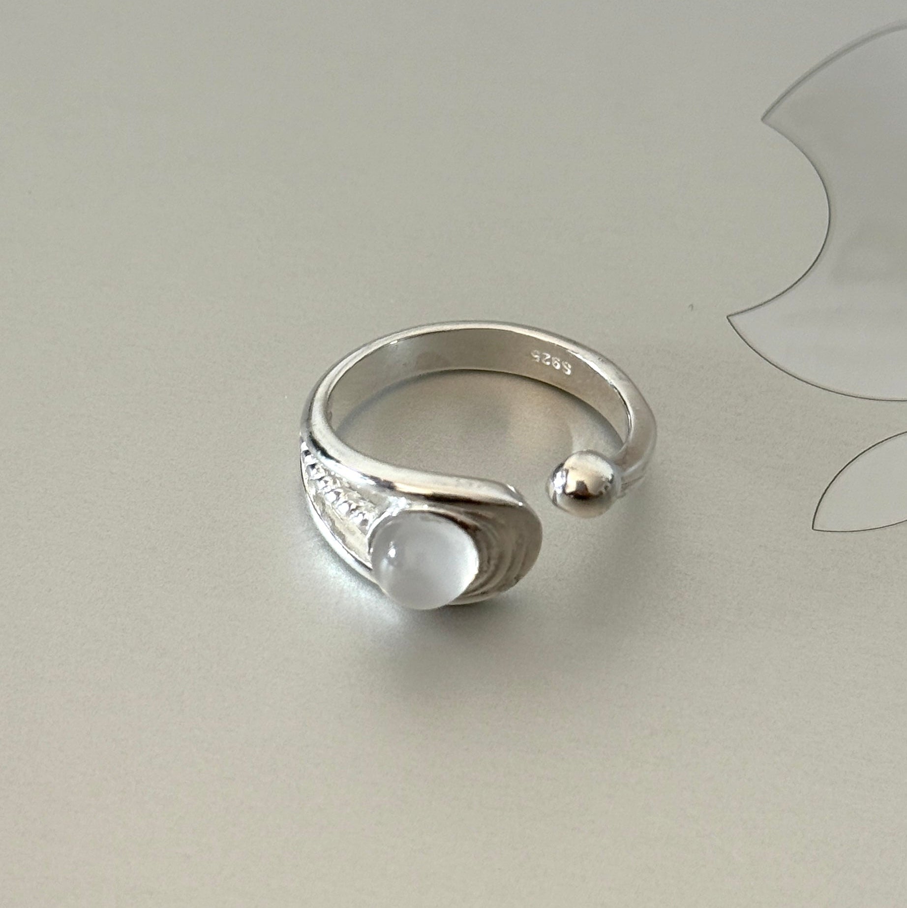 Close-up of the Tamsin ring, highlighting the detailed braided texture, the serene moonstone, and the delicate silver bead accent.