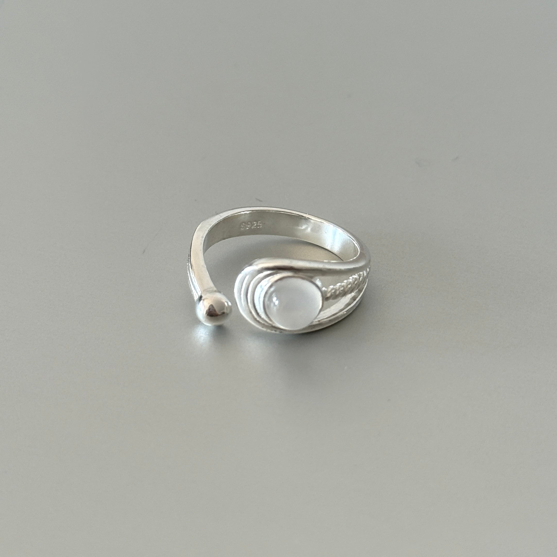 Close-up of the Tamsin ring, highlighting the detailed braided texture, the serene moonstone, and the delicate silver bead accent.